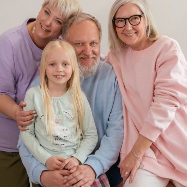 A happy multigenerational family posing indoors with smiles and affection.